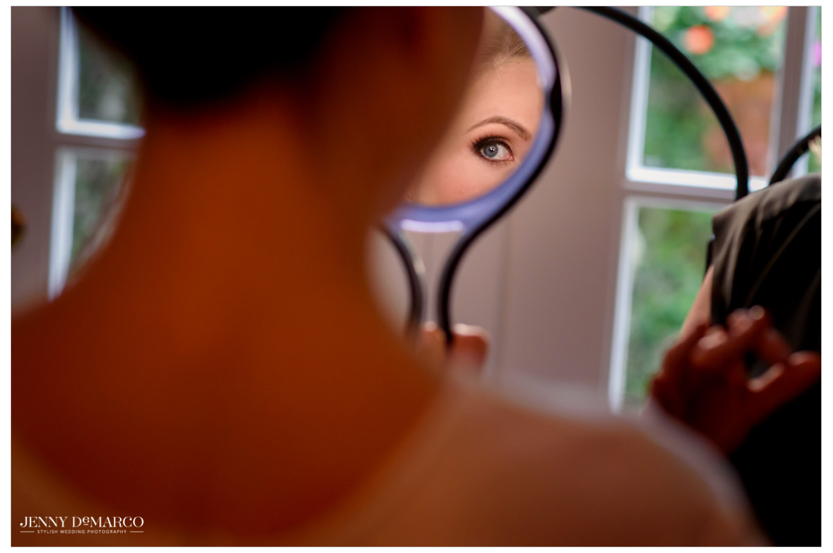 Bride looks at her makeup in the mirror.