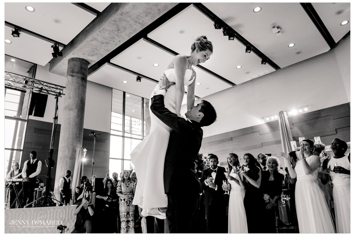 Grooms lifts his wife in the air.