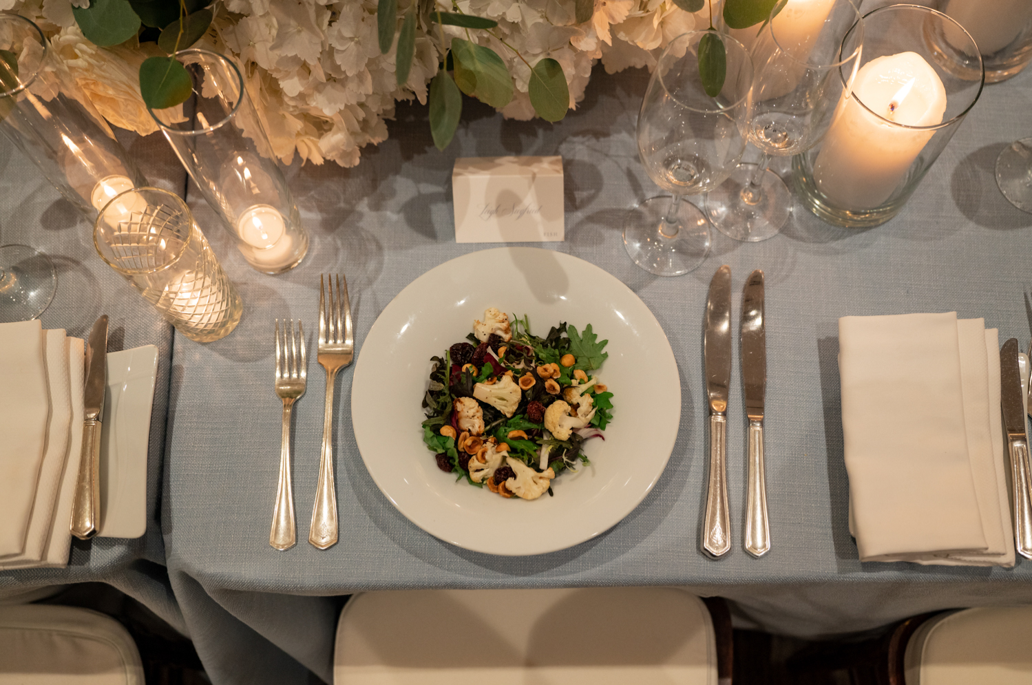 A colorful plated salad at the reception table, surrounded by candles and white florals.